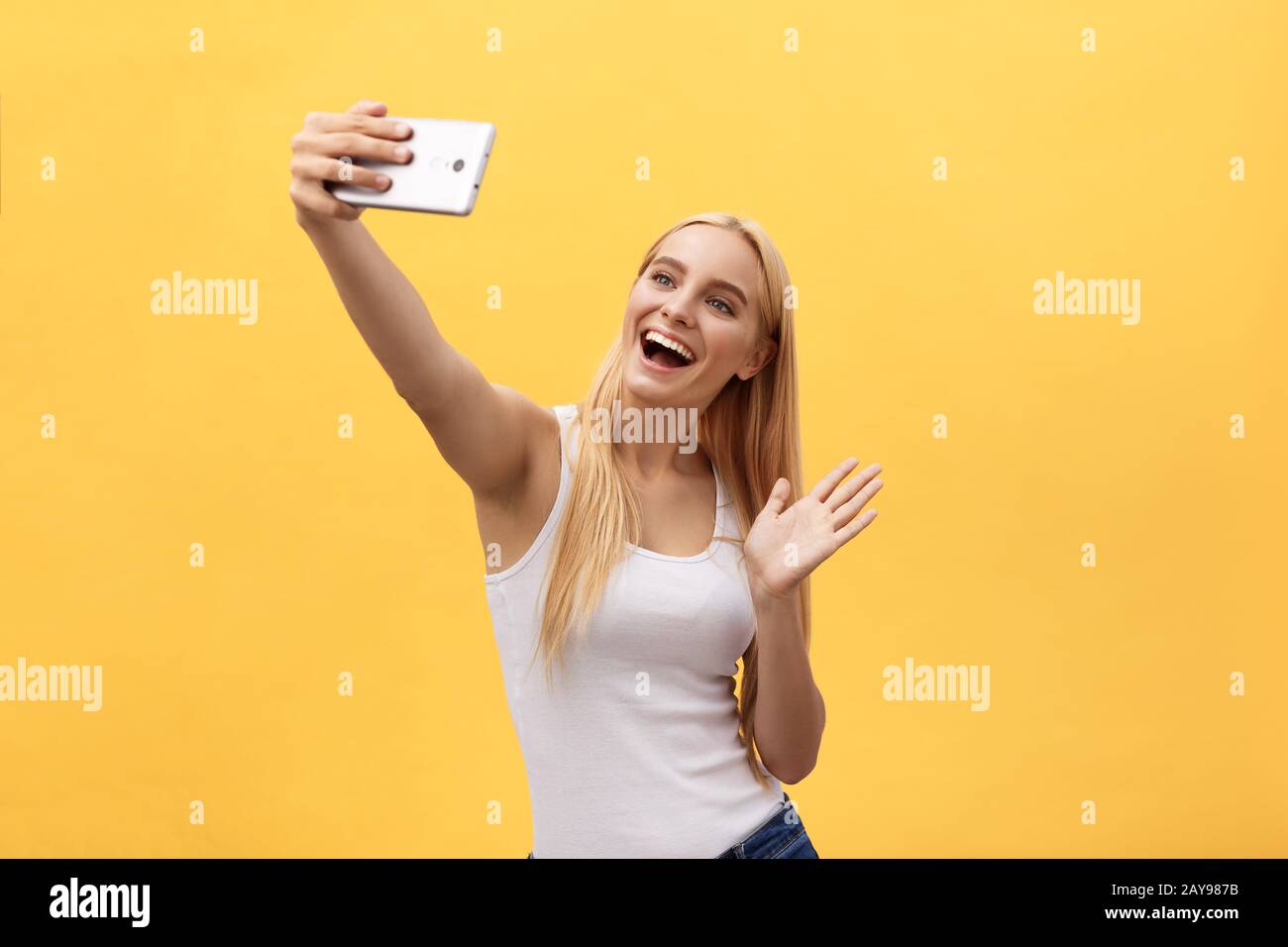 Giovane affascinante donna bionda con felice esce dalla faccia emozionale guardando la telecamera, isolate su sfondo giallo Foto Stock