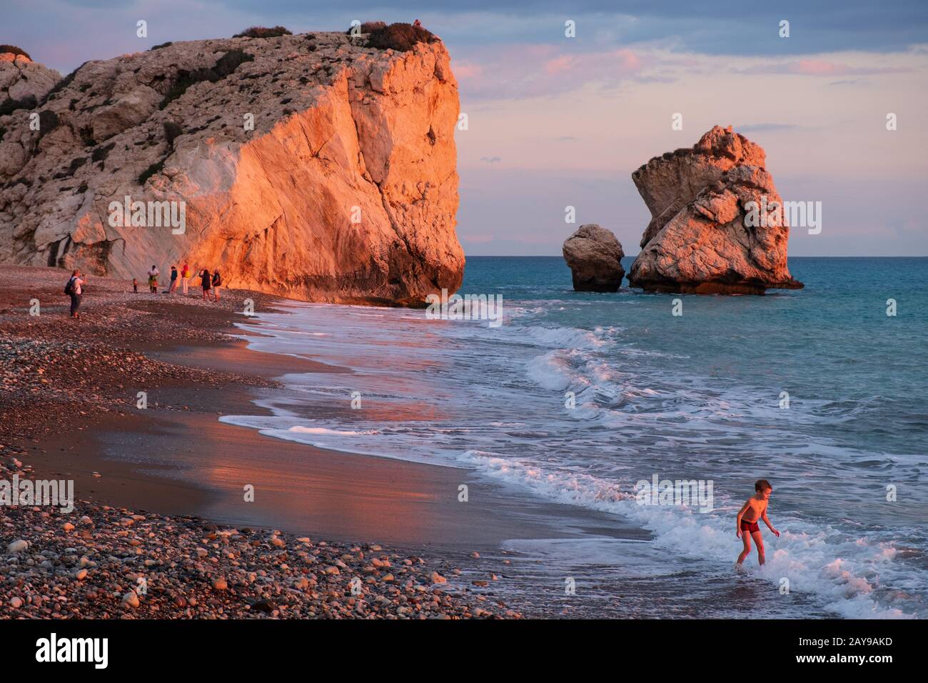 Un ragazzo gioca sulla spiaggia alle rocce Petra tou Romiou, a Paphos, Cipro. Foto Stock