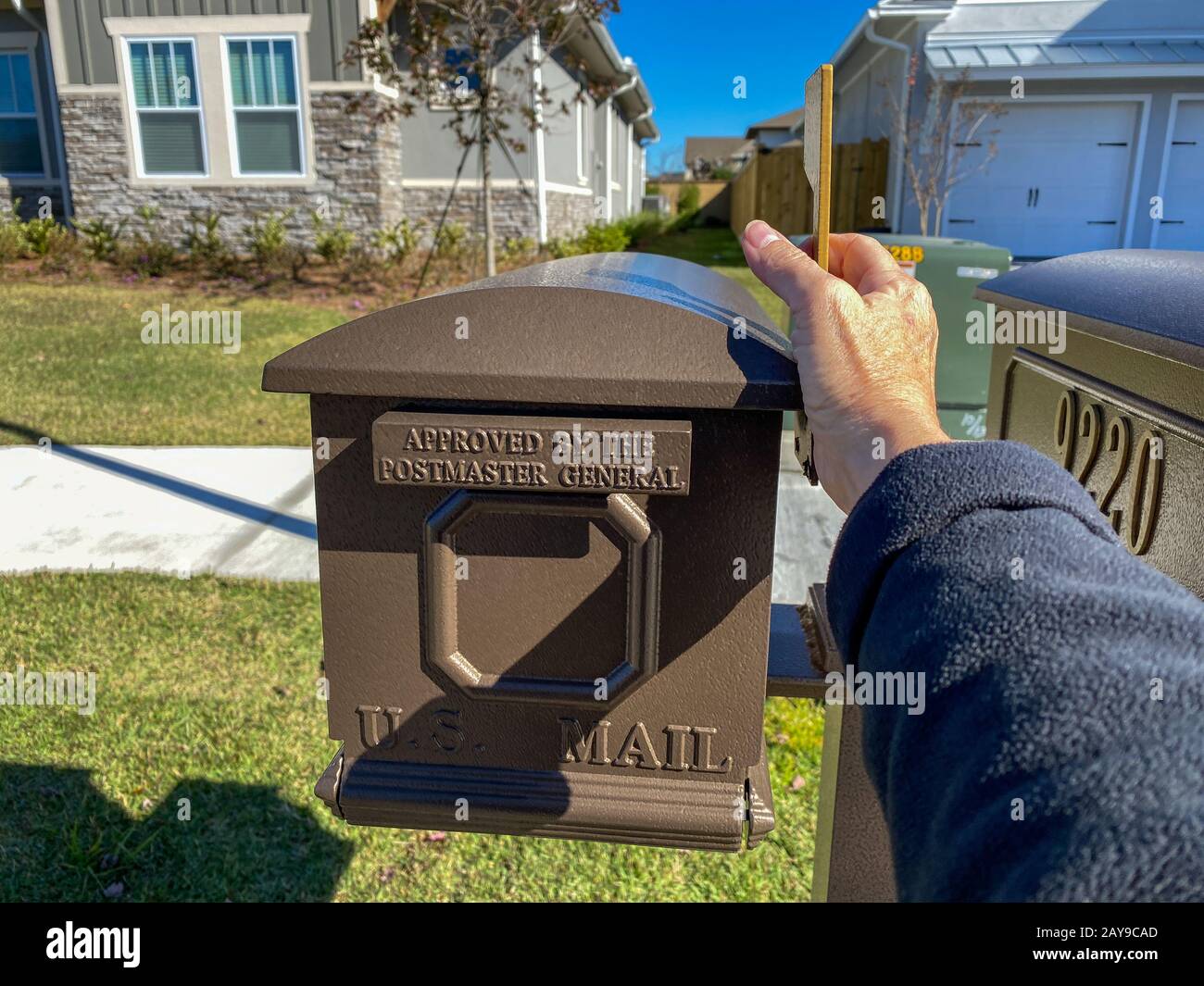 Orlando, FL/USA-2/8/20: Una mano che mette la bandiera su una scatola della posta degli Stati Uniti davanti ad una sede. Foto Stock