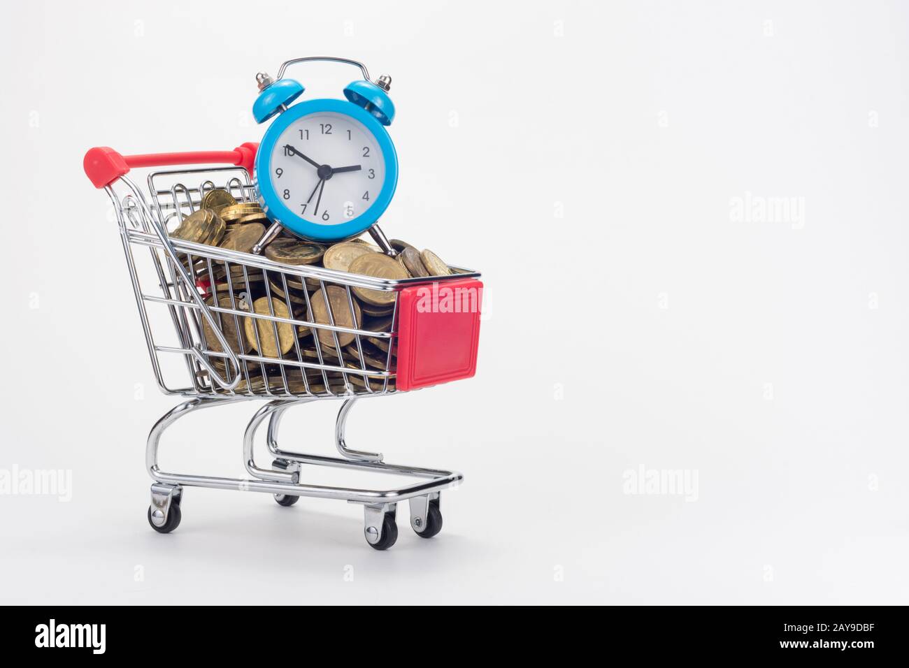 Il carrello del negozio del negozio è riempito con monete, con un piccolo orologio da tavolo in alto Foto Stock