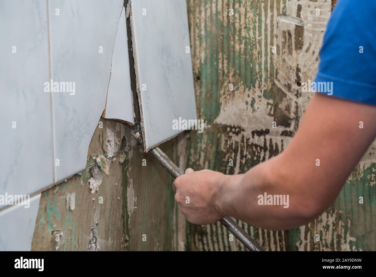 Il lavoratore di costruzione rimuove con le mattonelle di crowbar - primo piano di scalpellatura Foto Stock