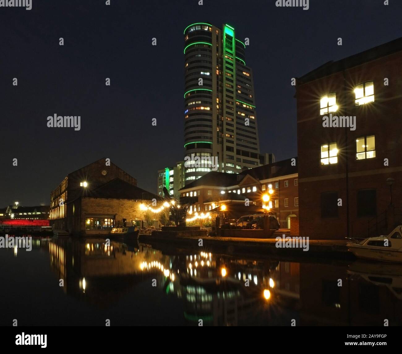 Vista del paesaggio urbano della banchina del canale a leeds di notte, con edifici illuminati e il ponte riflesso Foto Stock