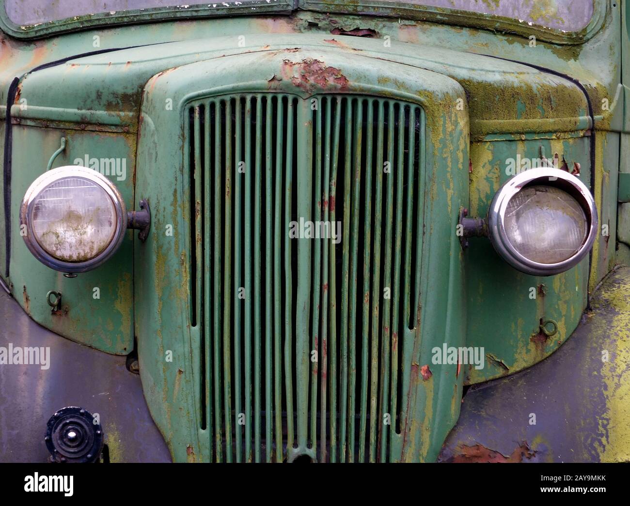 primo piano della parte anteriore di un vecchio camion verde arrugginito abbandonato coperto di muschio Foto Stock