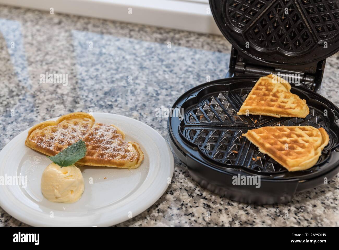 deliziosi waffle a forma di cuore preparati con gelato alla vaniglia Foto Stock