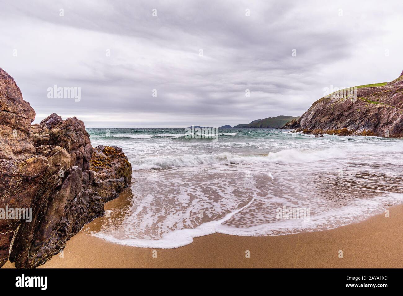 Piccola spiaggia nascosta tra rocce e isole in lontananza Foto Stock