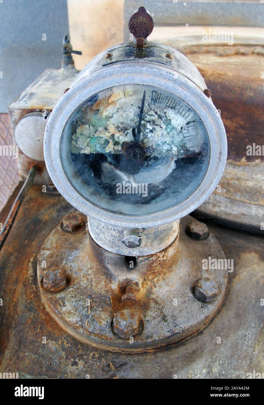 vecchio misuratore rotto montato su un vecchio motore industriale arrugginito abbandonato con bulloni Foto Stock