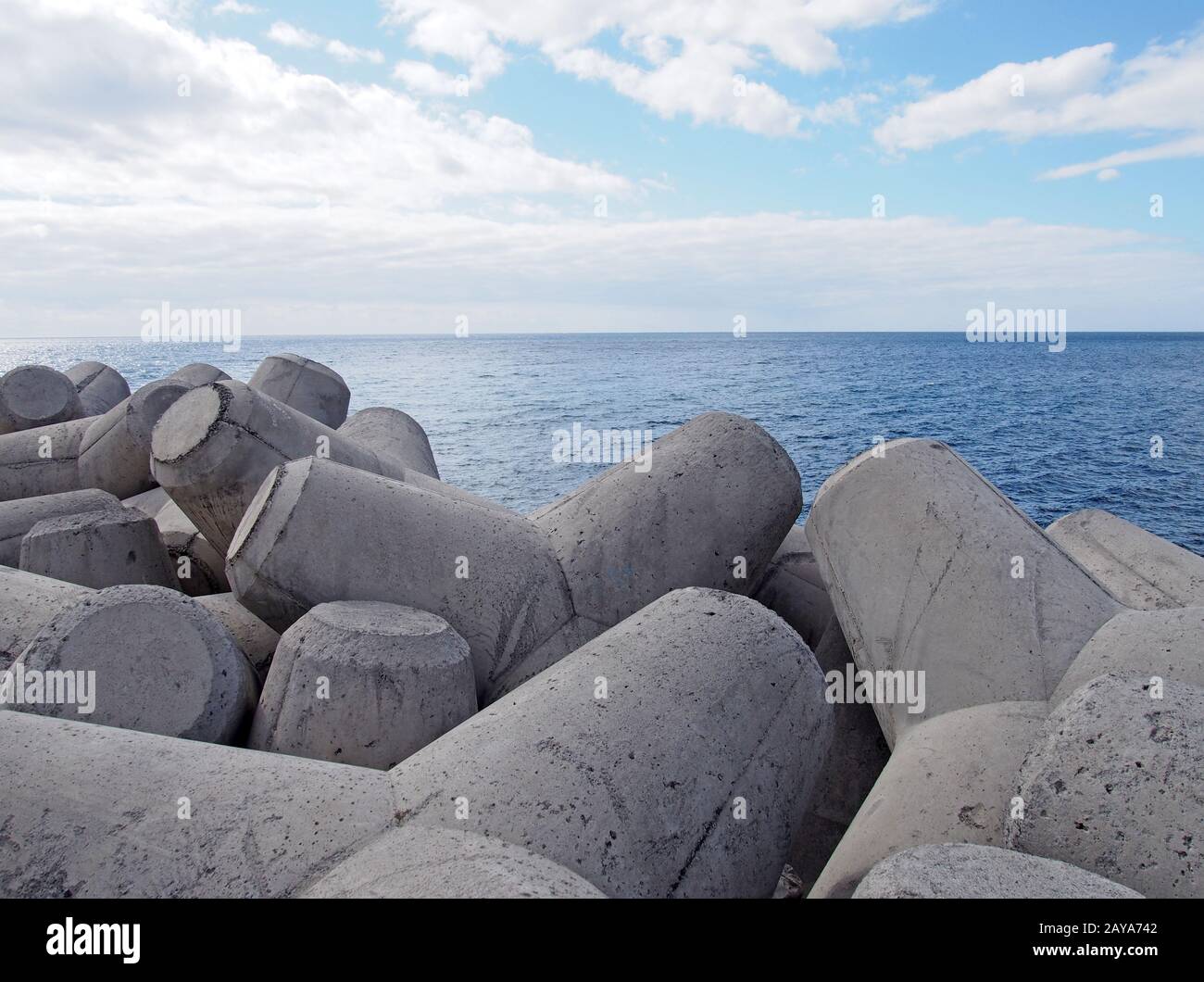 i tetrapodi interbloccanti in calcestruzzo usati per prevenire l'erosione costiera posta su una costa con un mare blu e un cielo soleggiato Foto Stock