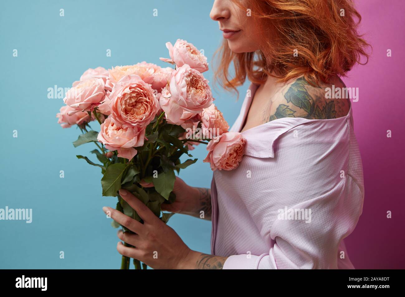 Rose rosa delicato nelle mani di una ragazza con un tatuaggio su un doppio sfondo rosa blu con spazio per la copia del testo. Presentazione di compleanno Foto Stock