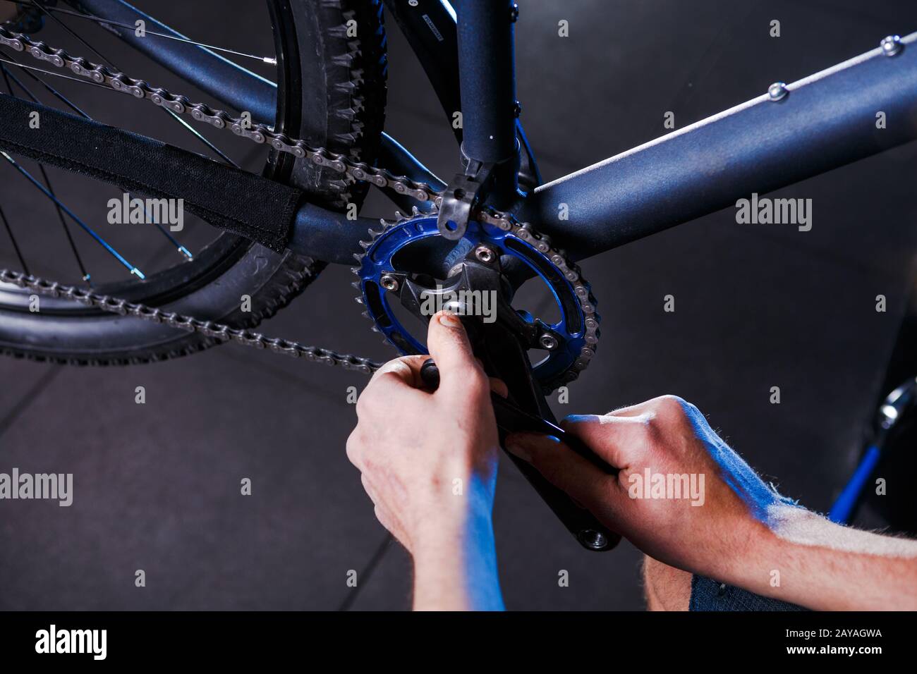 Primo piano delle mani dell'uomo la meccanica della bicicletta nel negozio usa l'istment per regolare e riparare il gruppo della pedivella della bicicletta, la cha della bicicletta Foto Stock