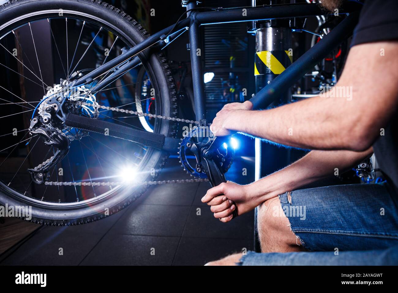 Primo piano delle mani dell'uomo la meccanica della bicicletta nel negozio usa l'istment per regolare e riparare il gruppo della pedivella della bicicletta, la cha della bicicletta Foto Stock