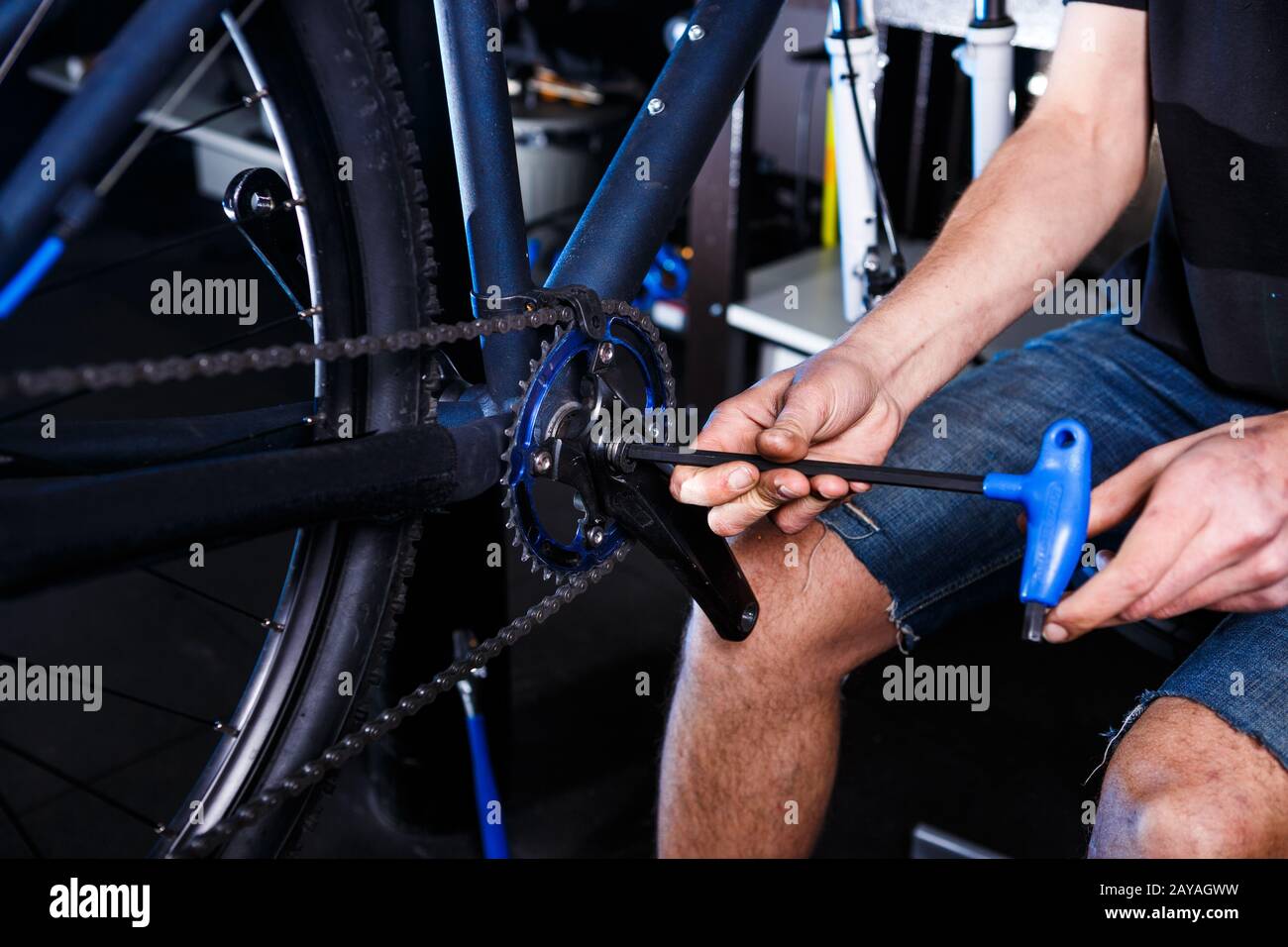 Primo piano delle mani dell'uomo la meccanica della bicicletta nel negozio usa l'istment per regolare e riparare il gruppo della pedivella della bicicletta, la cha della bicicletta Foto Stock