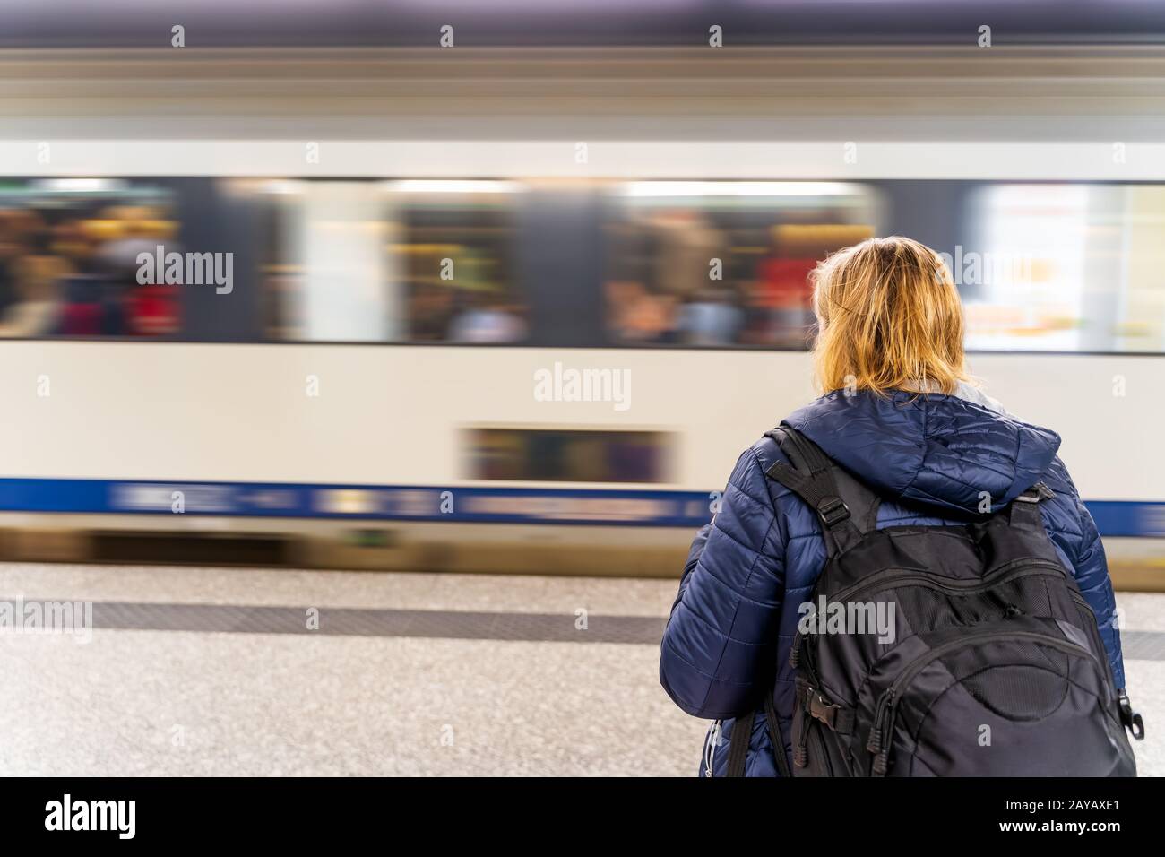 Donna in attesa di un treno in una stazione della metropolitana non riconoscibile, movimento sfocato Foto Stock