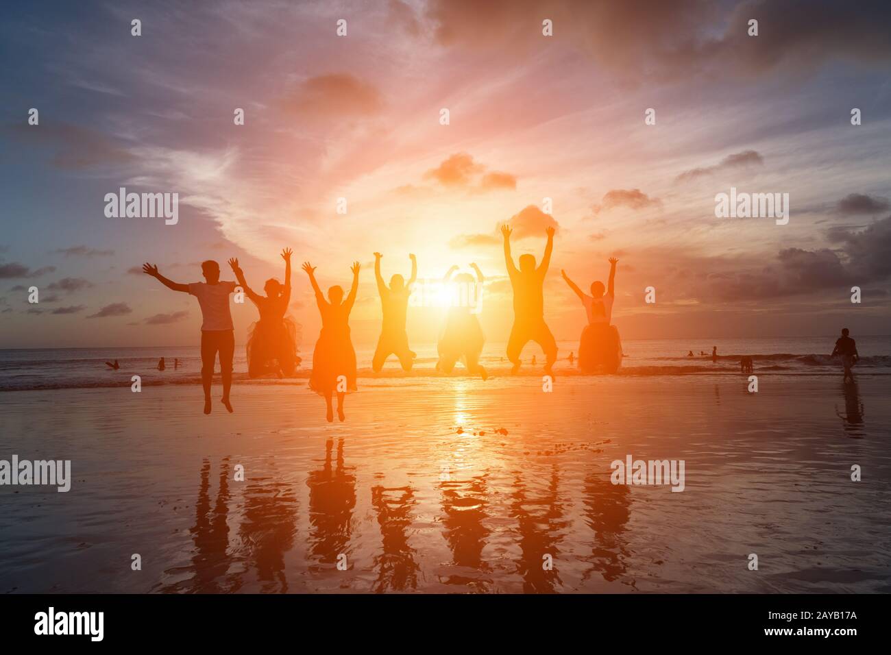 gruppo di amici felici che saltano sulla spiaggia contro il tramonto Foto Stock