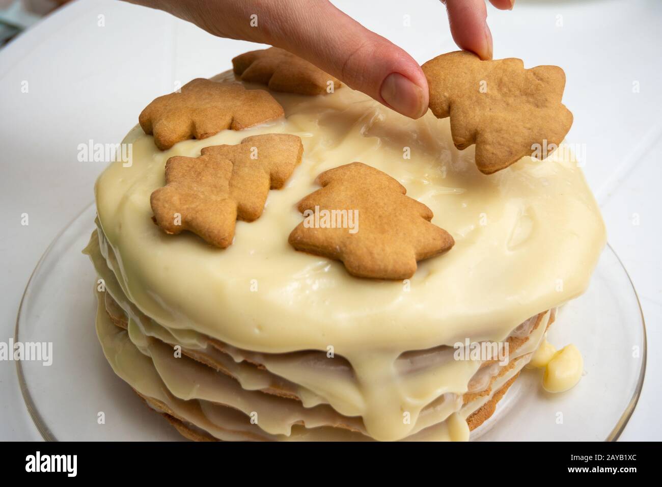 Torte fatte in casa con il latte condensato, una mano sulla parte superiore mette un albero di Natale cookie Foto Stock