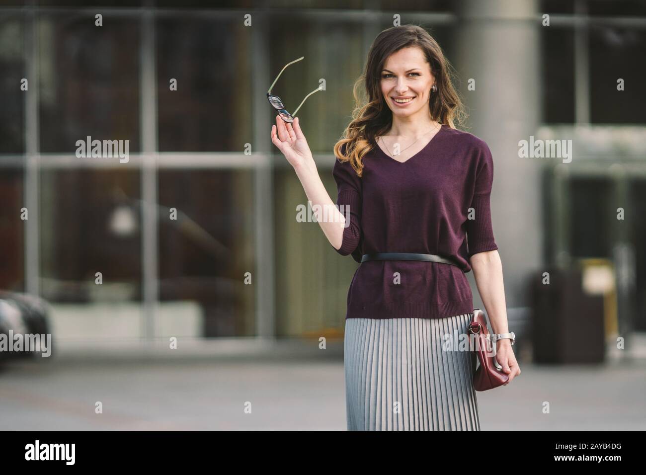 Donna d'affari in piedi sulla strada contro l'edificio degli uffici. City business donna che lavora. Ritratto donna d'affari sorridente con gla Foto Stock