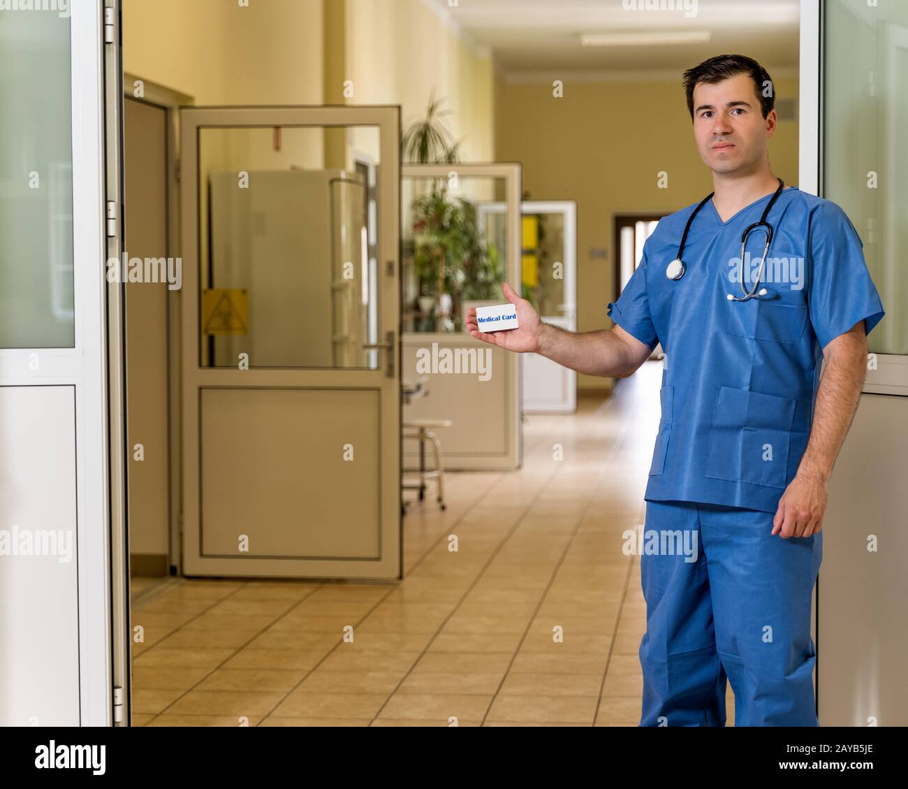 Medico di mezza età maschile in scrub blu che tiene carta medica Foto Stock