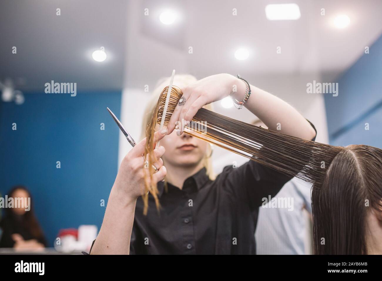 parrucchiere che tiene forbici e pettine e fa cliente donna taglio di capelli. Giovane bella donna capelli tagliati in salone di bellezza. Processo di Foto Stock