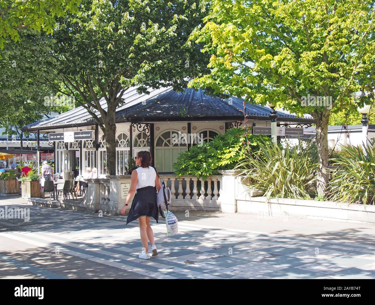 una donna che cammina davanti ai caffè all'aperto in lord street a southport merseyside Foto Stock