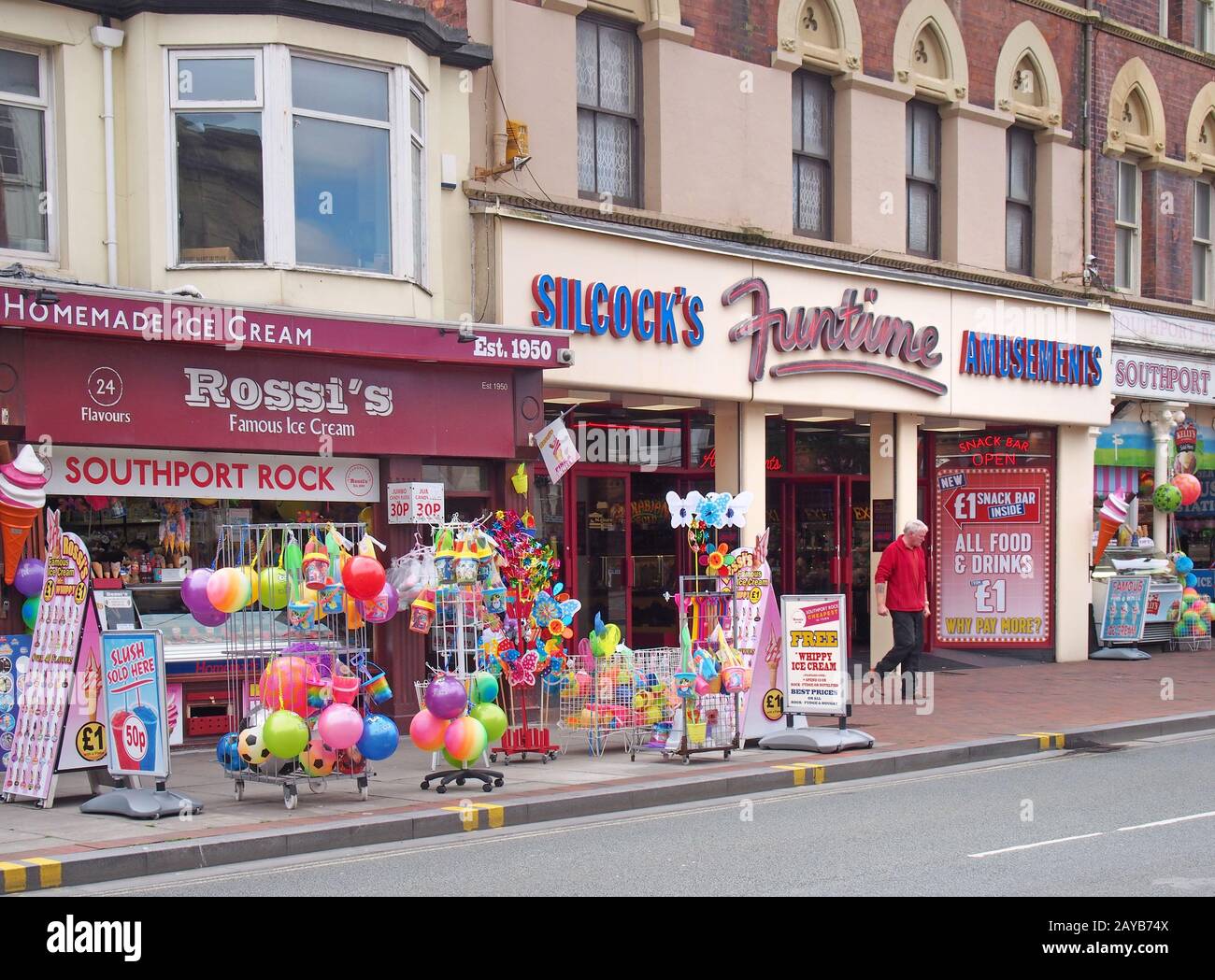 un negozio in neville street a southport merseyside vendere gelati rock beach giocattoli e spuntini con un uomo che cammina fuori da un divertente Foto Stock