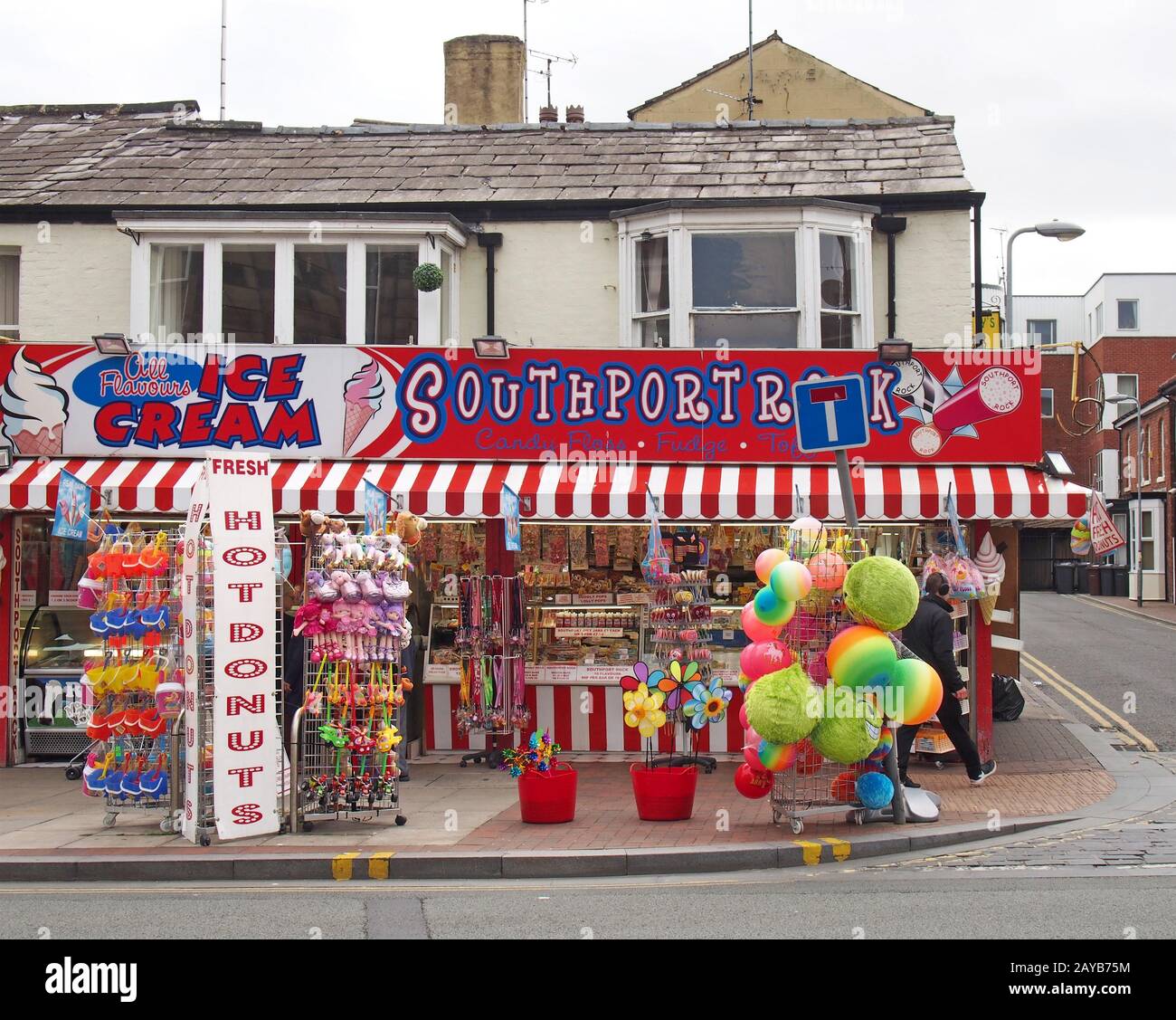 l'uomo passa davanti ad un negozio in via neville a southport merseyside che vende ciambelle di roccia di gelato e giocattoli da spiaggia Foto Stock