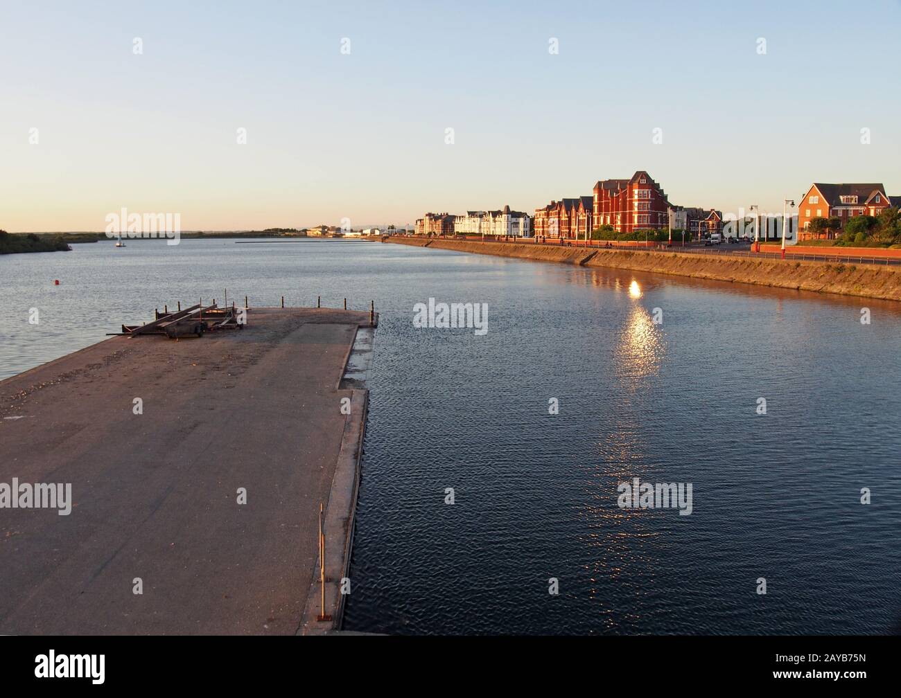 una vista sul lago a southport al tramonto con un molo di fronte agli edifici sul lungomare Foto Stock