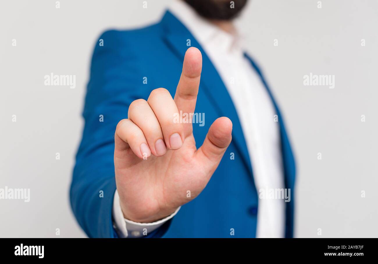 Uomo d'affari in suite blu e camicia bianca puntando con un dito nello spazio vuoto. Copia spazio con businessman che punta con il dito. Foto Stock