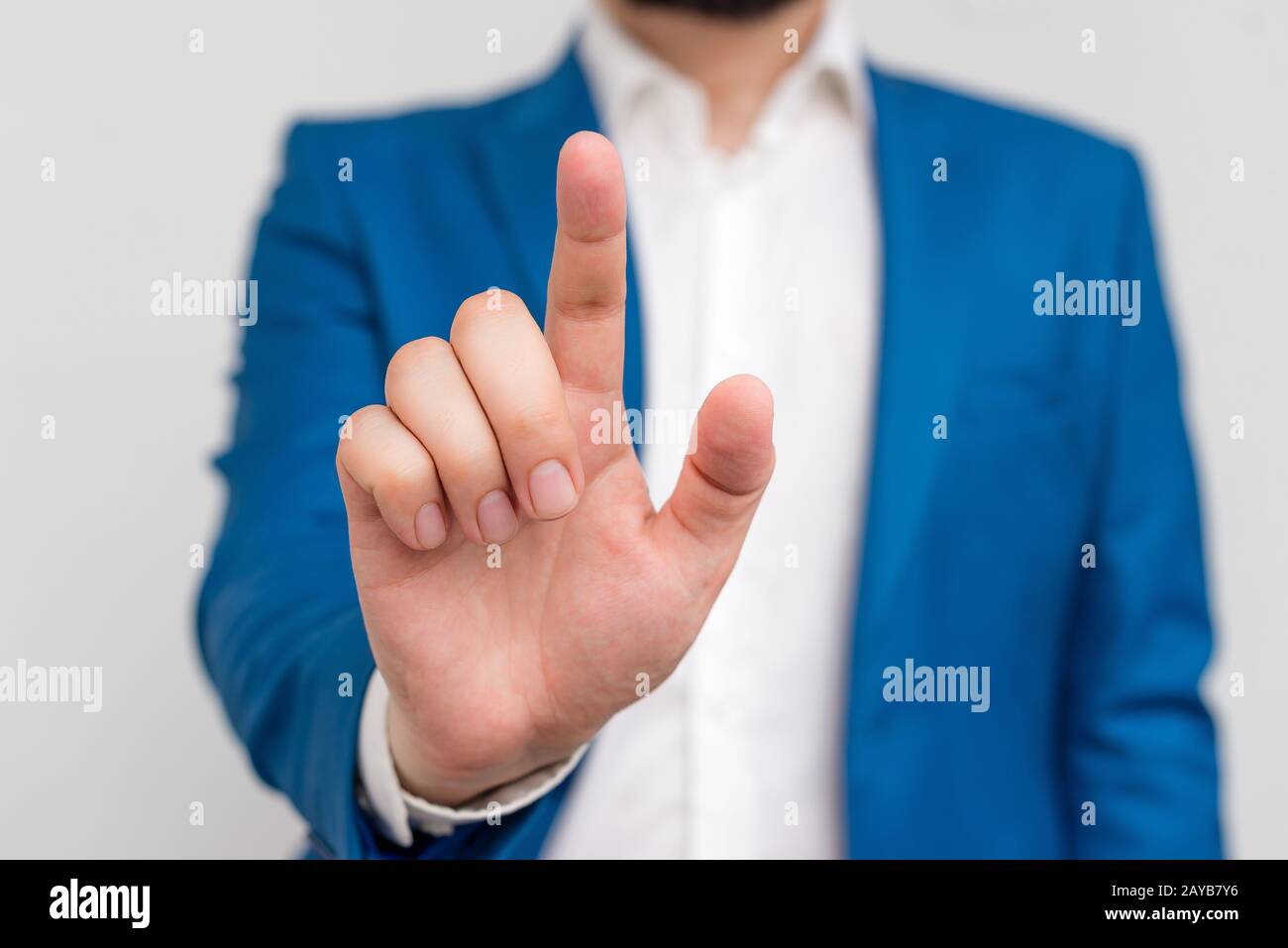 Uomo d'affari in suite blu e camicia bianca puntando con un dito nello spazio vuoto. Copia spazio con businessman che punta con il dito. Foto Stock