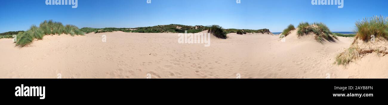 una lunga vista panoramica sulle dune di sabbia costiere ricoperte di erba di fronte al mare a formby merseyside in una luminosa giornata estiva wi Foto Stock