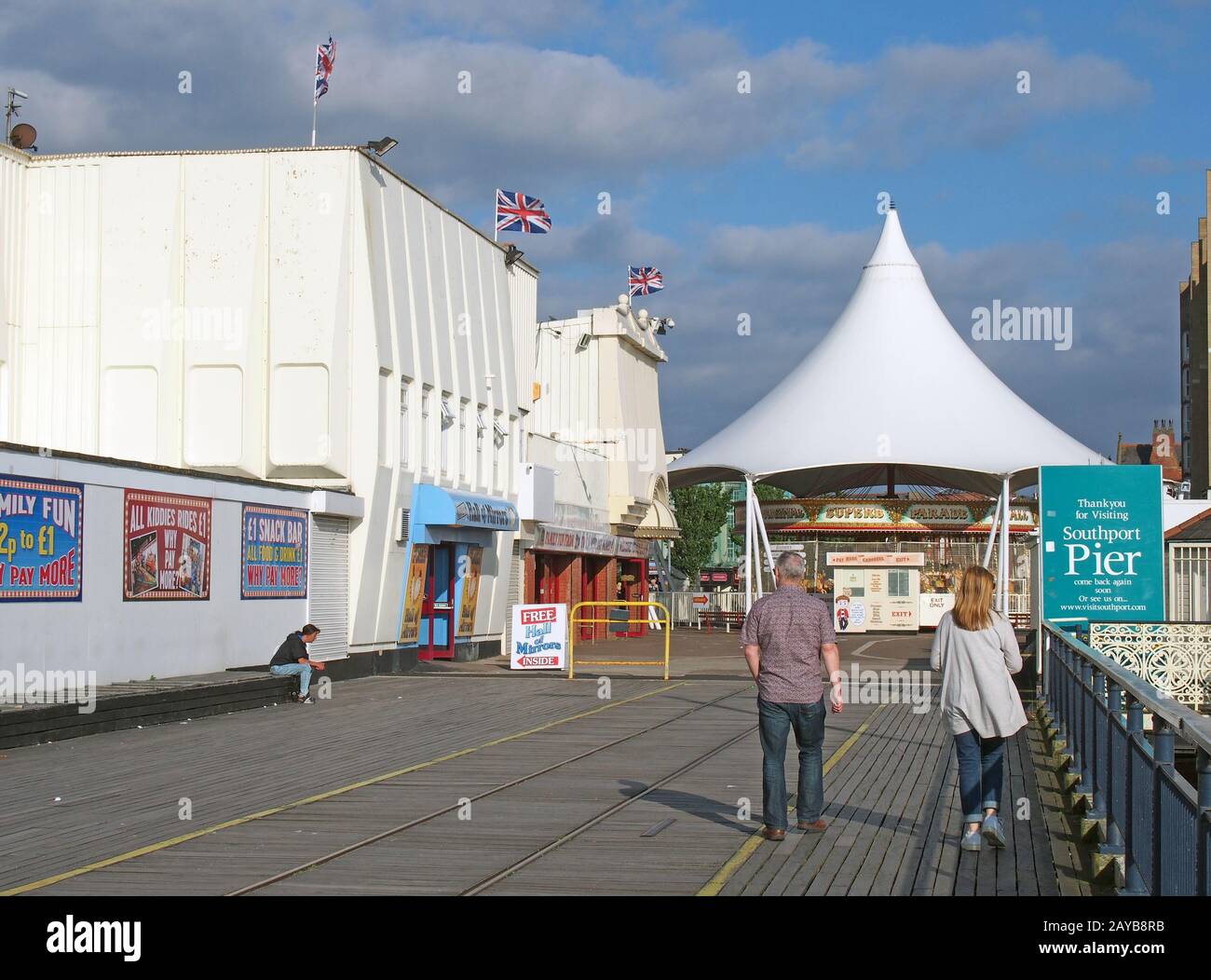 persone che camminano all'ingresso del molo di southport a merseyside con una giostra e una galleria di divertimenti Foto Stock
