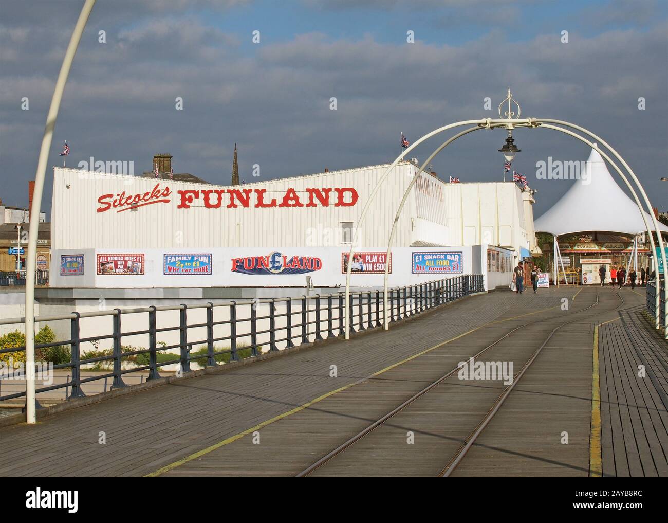 persone che camminano all'ingresso del molo di southport a merseyside con una giostra e una galleria di divertimenti Foto Stock