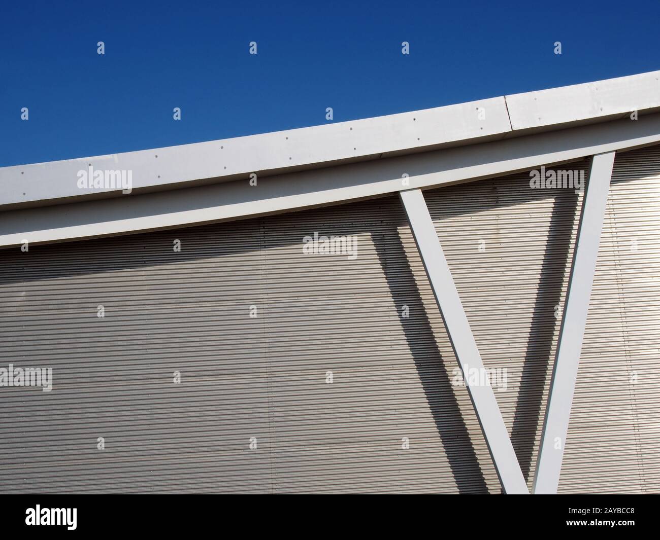 rivestimento metallico su un moderno edificio industriale con travi in acciaio e travi del tetto curve contro un cielo blu Foto Stock