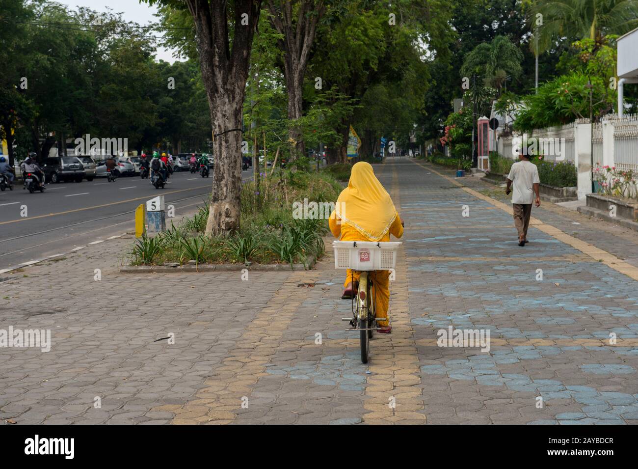 Street scene con una donna musulmana che ridendo una bicicletta a solo, una città su Java, Indonesia. Foto Stock