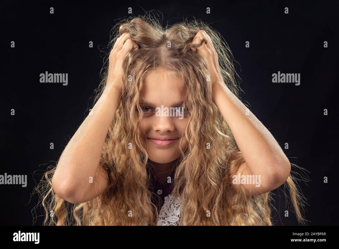 Dieci-anno-vecchia ragazza scuote le mani con lunghi capelli biondi Foto Stock