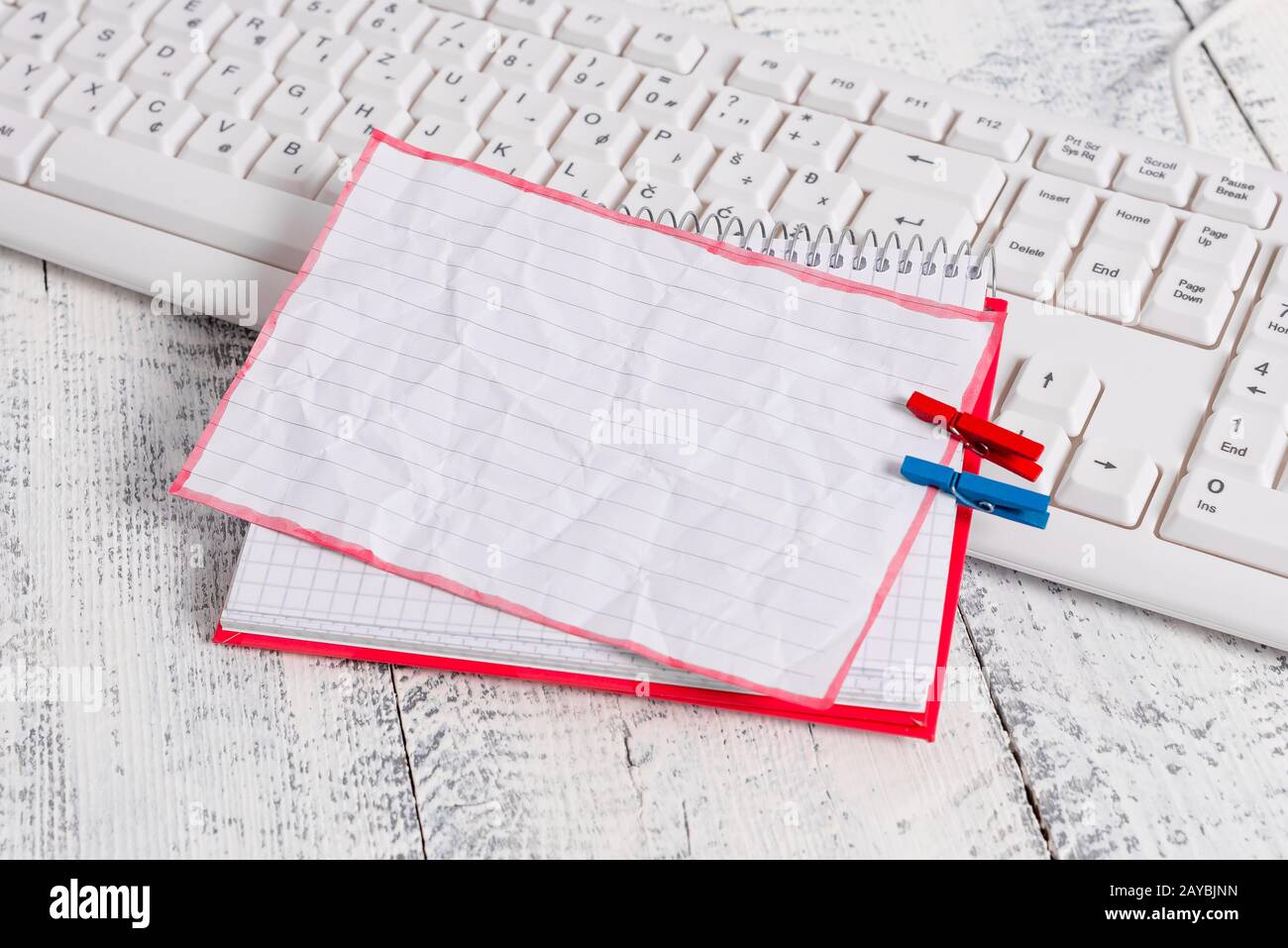 Quaderno di carta quadrato con una nota vuota a forma di rettangolo sopra fissata da due zoccoli sul foglio. Tastiera bianca sotto una c Foto Stock