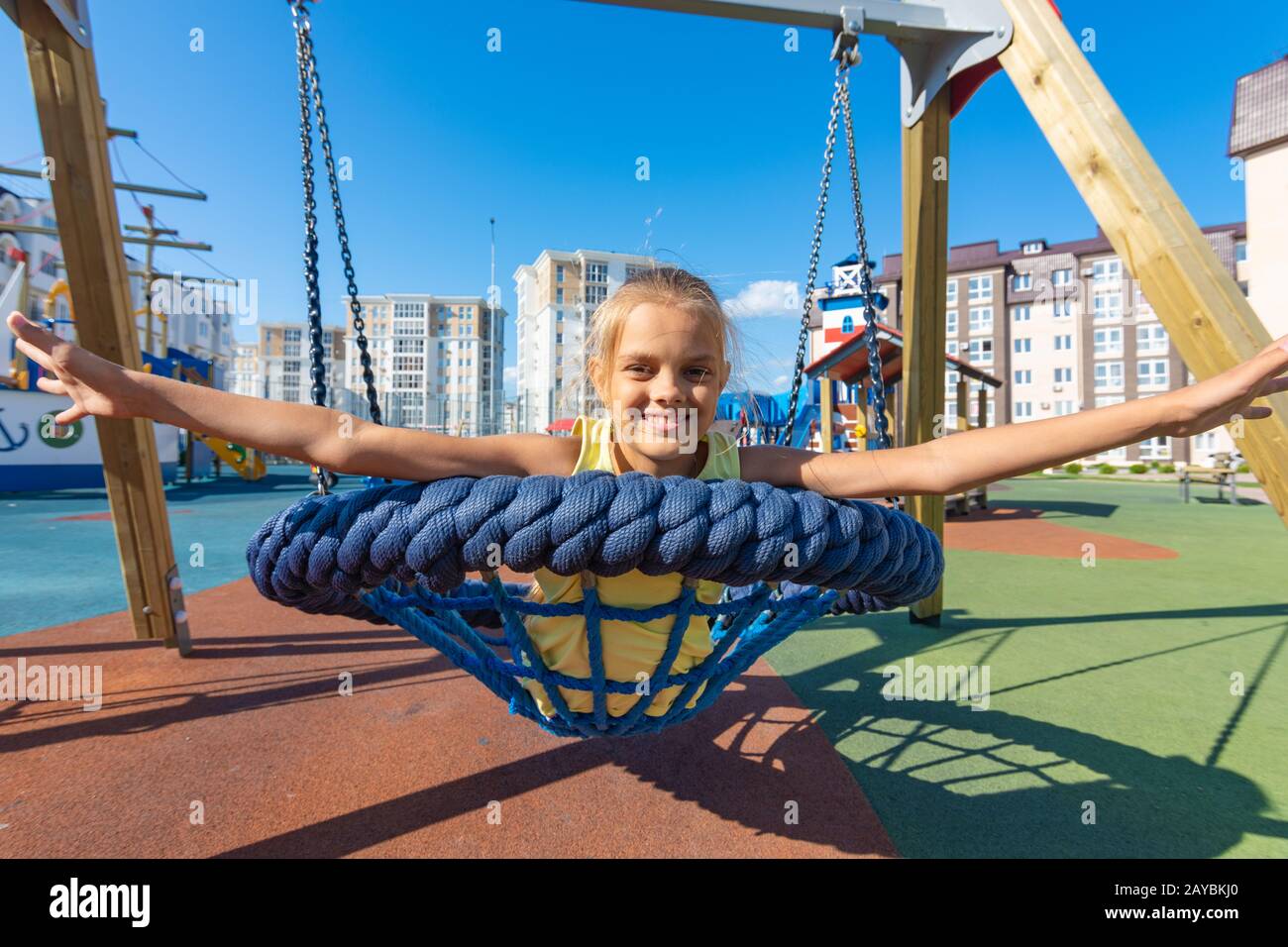 Ragazza con gioia la diffusione le braccia mentre cavalcate un round appeso swing Foto Stock