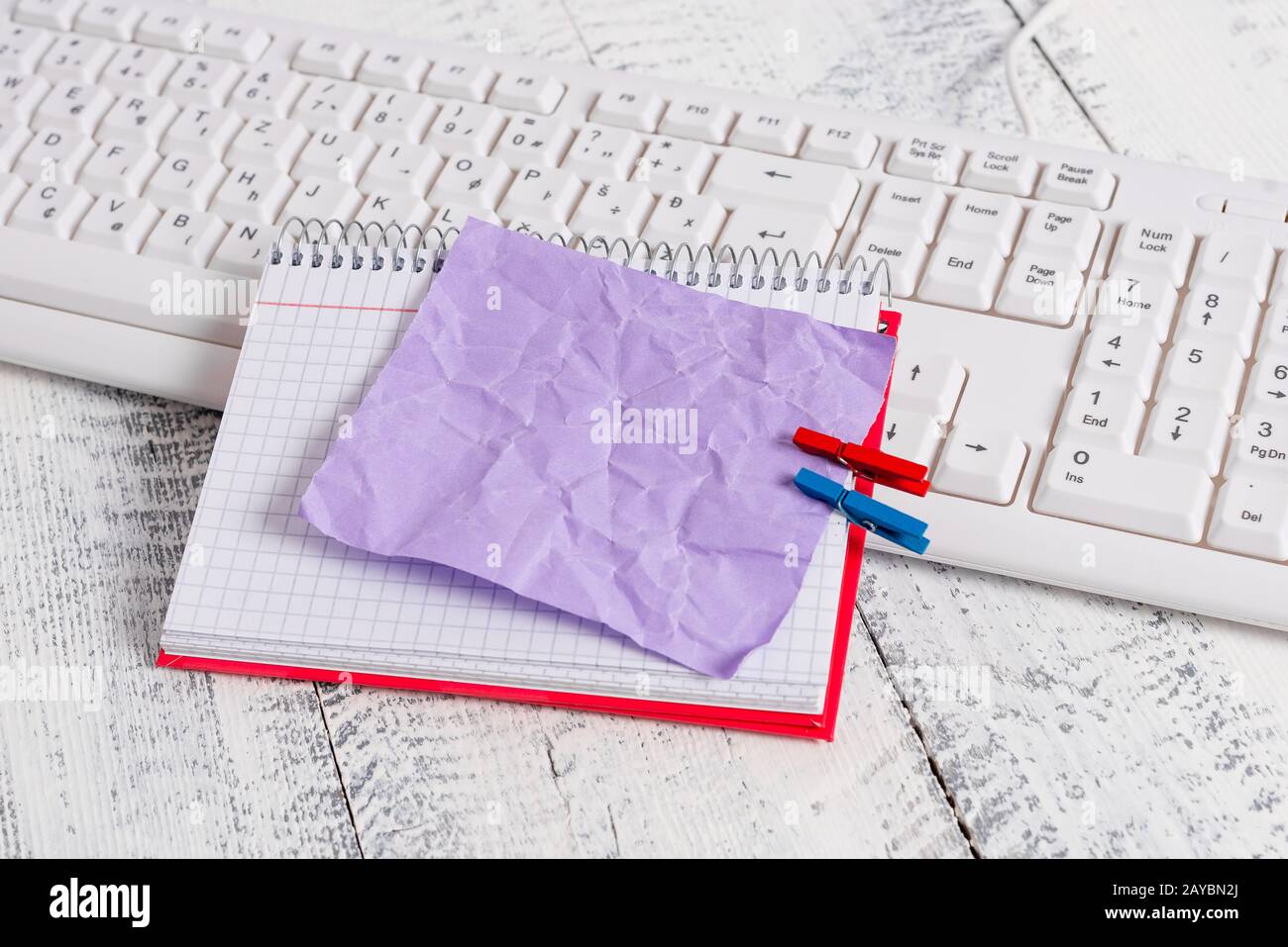 Quaderno di carta quadrato con una nota vuota a forma di rettangolo sopra fissata da due zoccoli sul foglio. Tastiera bianca sotto una c Foto Stock
