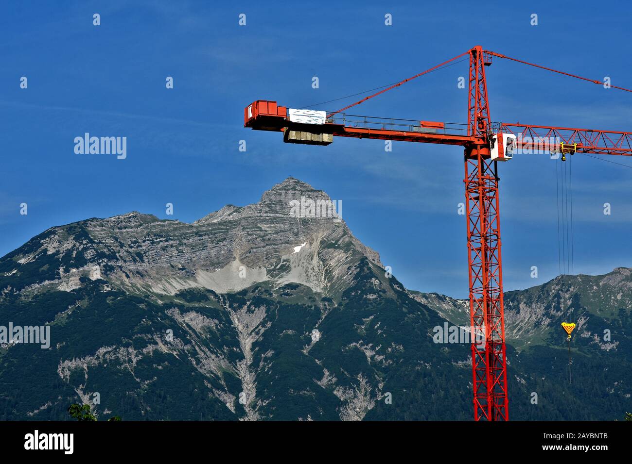 costruzione di gru di fronte al paesaggio alpino Foto Stock