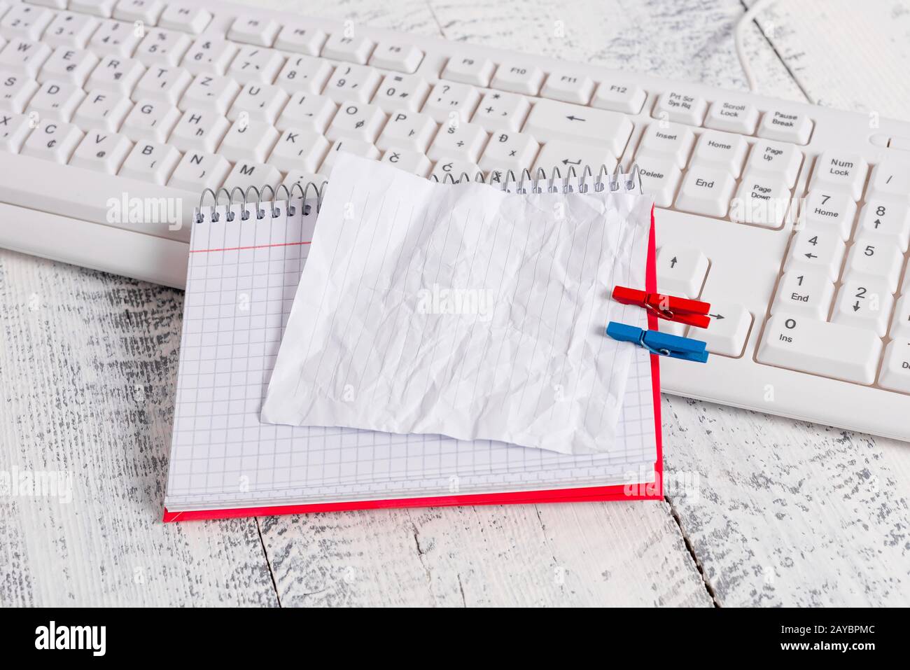Quaderno di carta quadrato con una nota vuota a forma di rettangolo sopra fissata da due zoccoli sul foglio. Tastiera bianca sotto una c Foto Stock