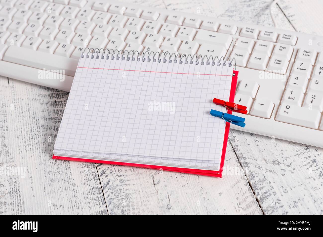Quaderno di carta quadrato con una nota vuota a forma di rettangolo sopra fissata da due zoccoli sul foglio. Tastiera bianca sotto una c Foto Stock