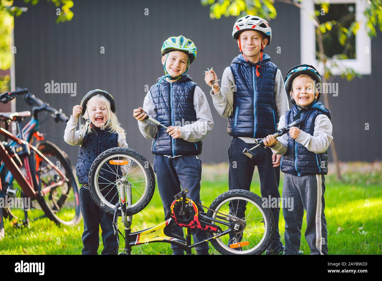 Meccanica per bambini, riparazione biciclette. Felici bambini che fissano bici insieme all'aperto in giornata di sole. Concetto di riparazione della bicicletta. Famiglia di lavoro di squadra Foto Stock