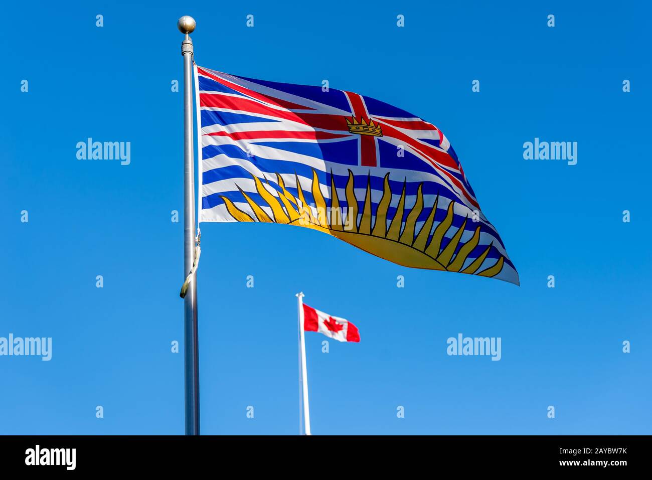 Bandiera della Columbia Britannica che vola con bandiera Canadese in background in una giornata di sole con cielo blu Foto Stock