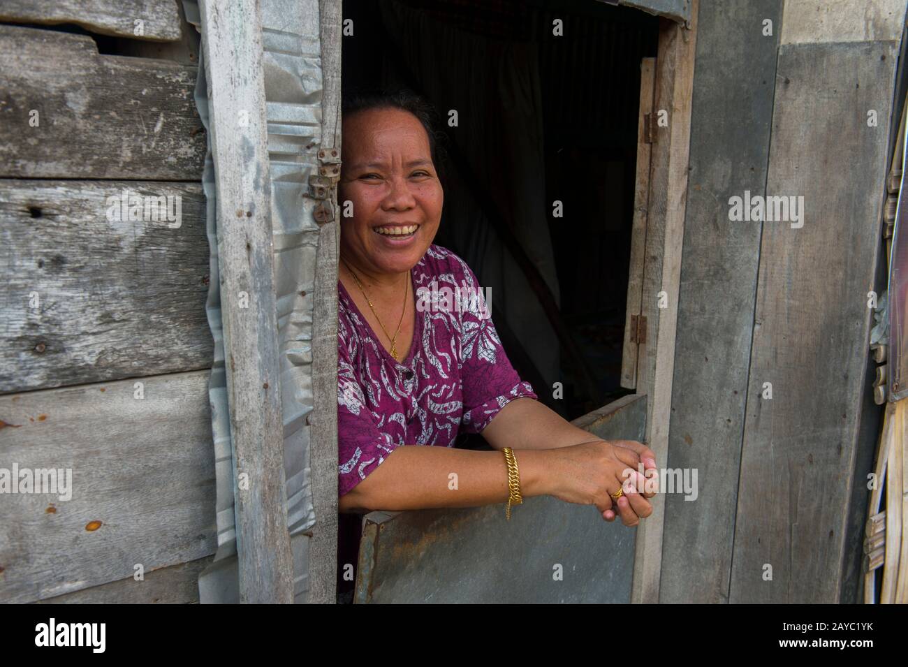 Una scena di villaggio con una donna che guarda fuori da una finestra di una casa nel villaggio gitana del mare di Bajau sull'isola di Bungin, famosa per vivere in case di palafitta abone Foto Stock