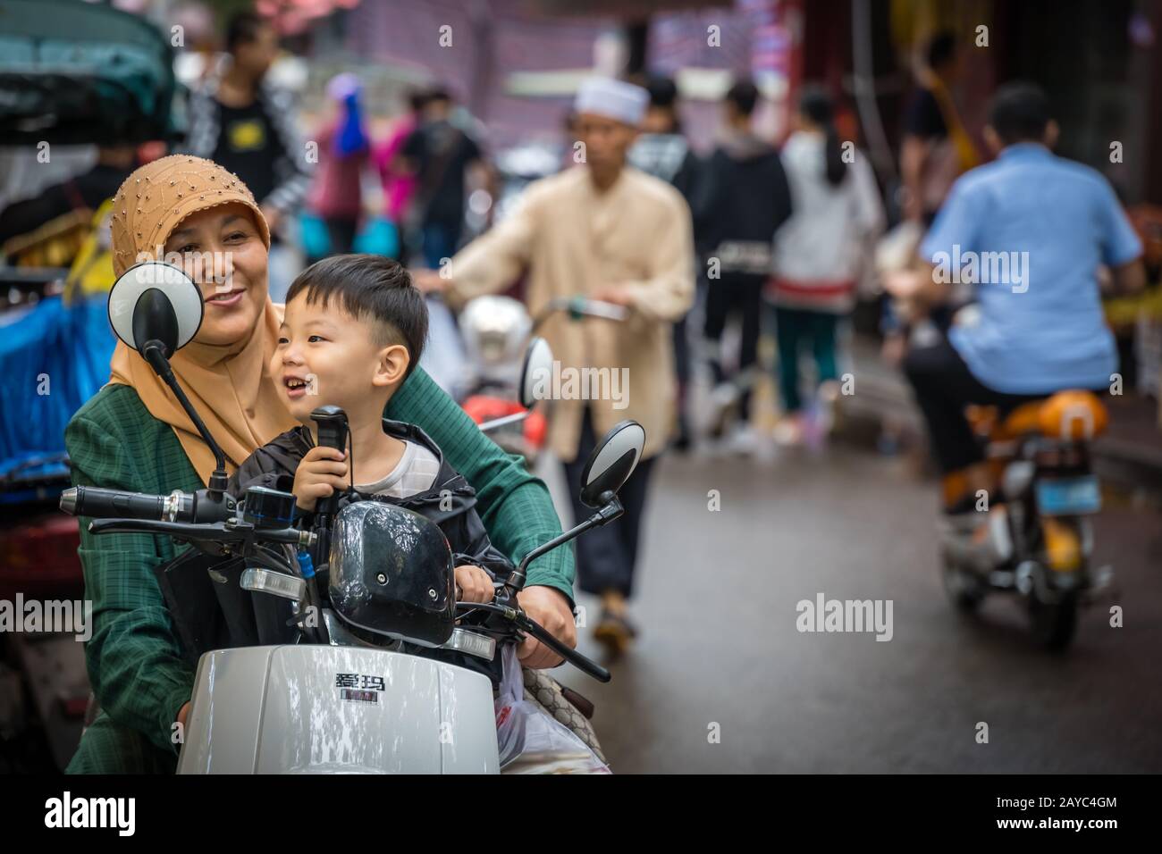 Donna musulmana con suo figlio su uno scooter Foto Stock