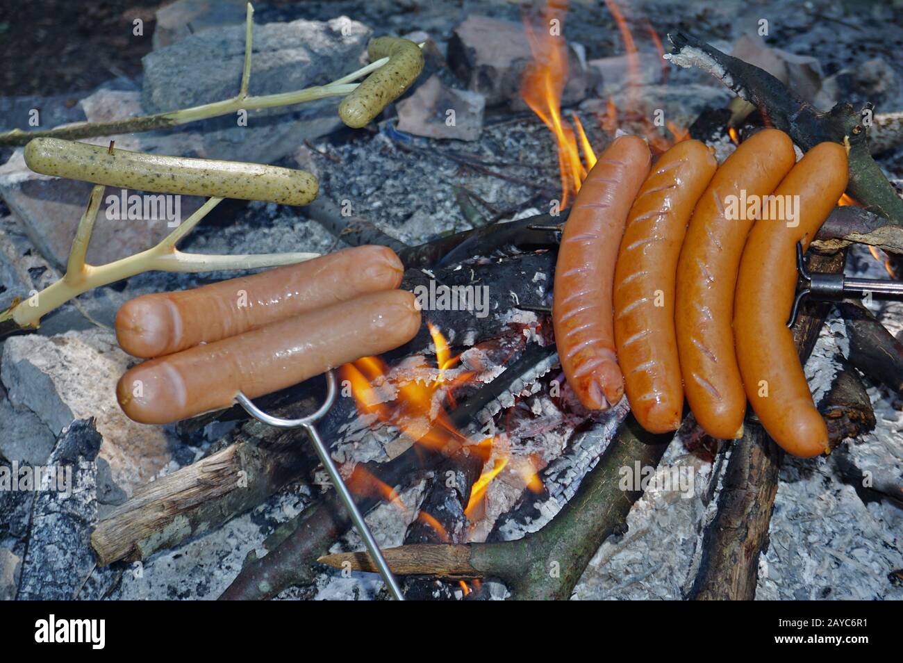 Grigliate le salsicce intorno al fuoco, Foto Stock