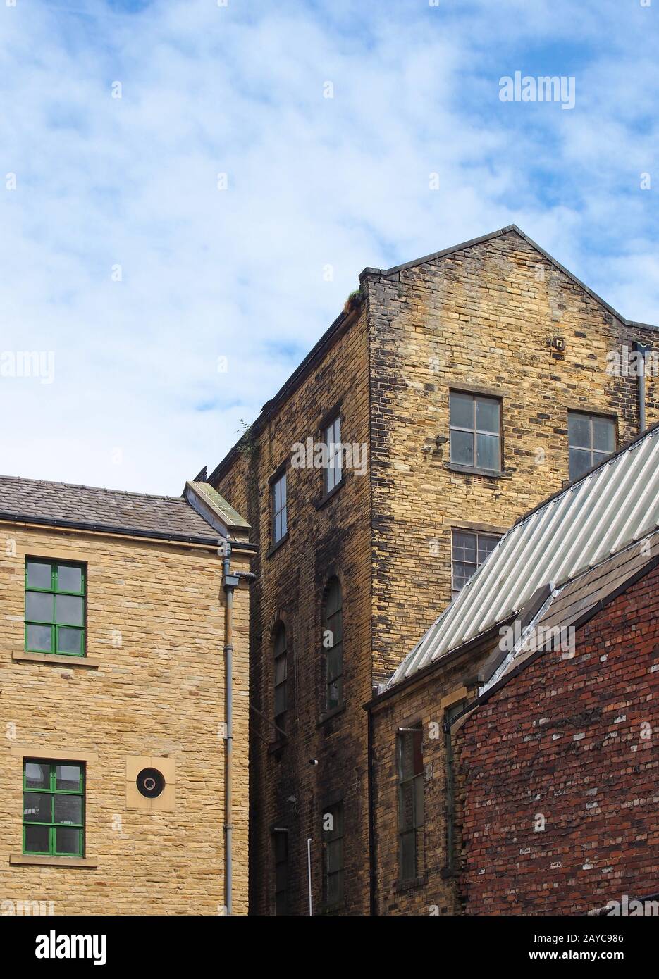 vecchio magazzino in pietra del 19 ° secolo e edifici di fabbrica a bradford west yorkshire contro un cielo blu nuvoloso Foto Stock