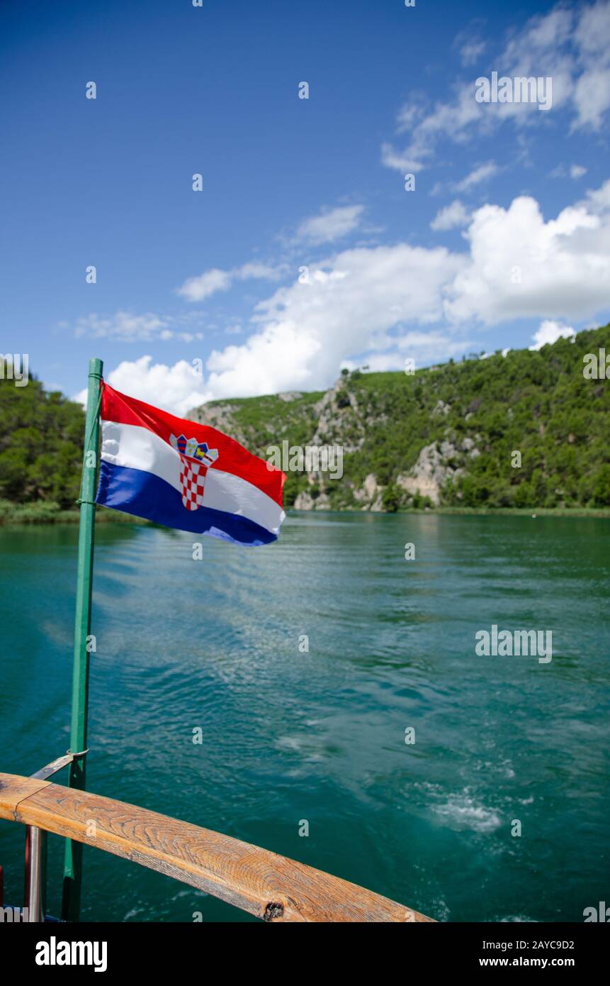 Barca su un fiume per le Cascate di Krka parco nazionale. Bandiera croata Foto Stock