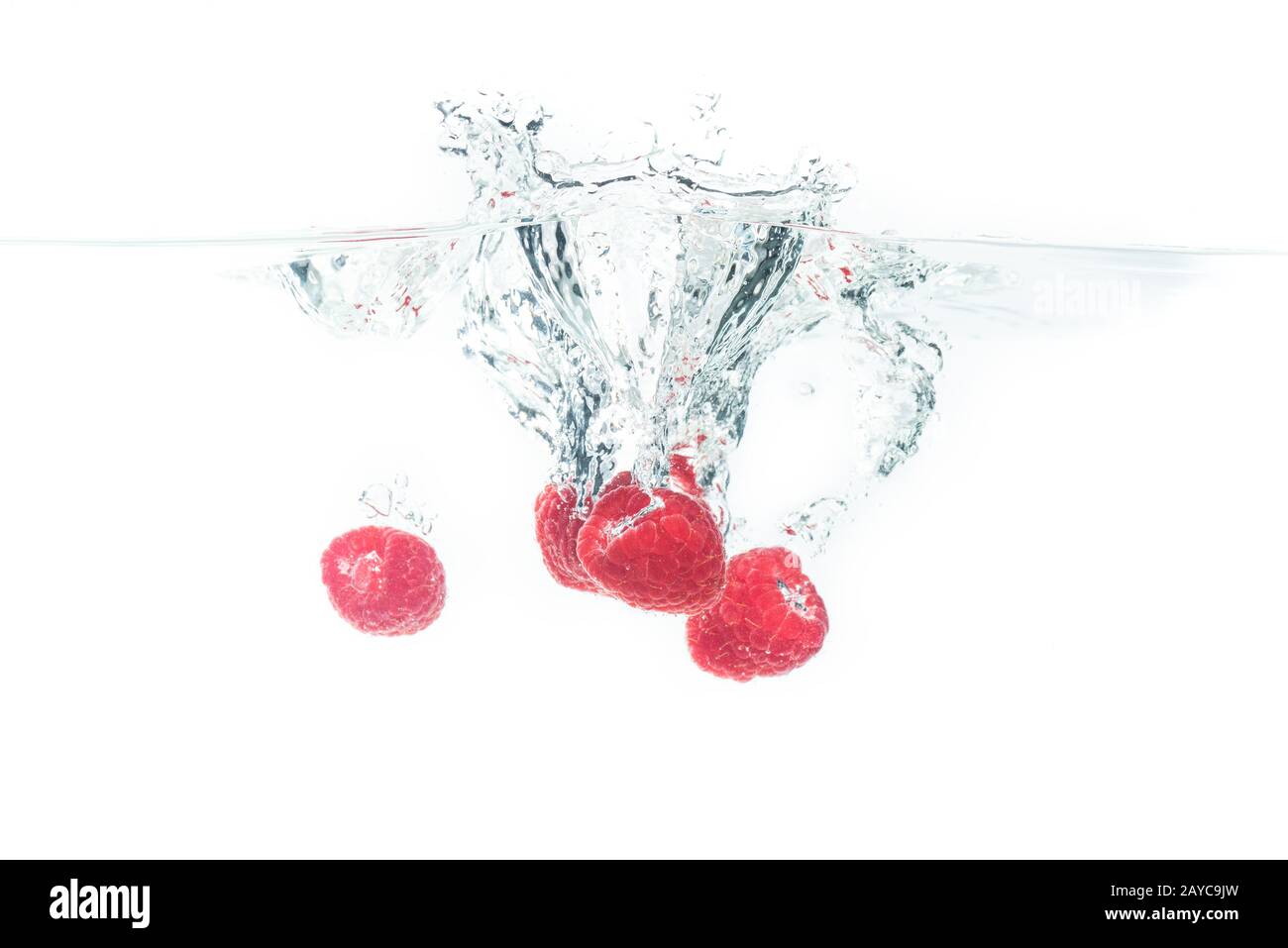 Mazzo di lamponi che spruzzano sulla superficie dell'acqua e che affondano. Isolato su sfondo bianco, splash food fotografia. Foto Stock