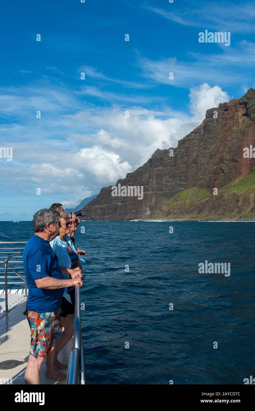Persone in barca per escursioni che guardano la costa di Na Pali sul lato occidentale dell'isola hawaiana di Kauai, Hawaii, USA. Foto Stock