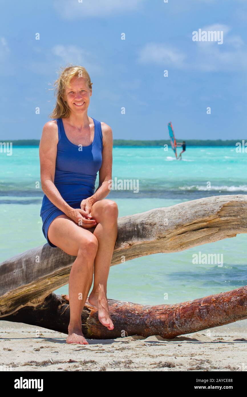 Donna olandese siede sul tronco dell'albero alla spiaggia Foto Stock
