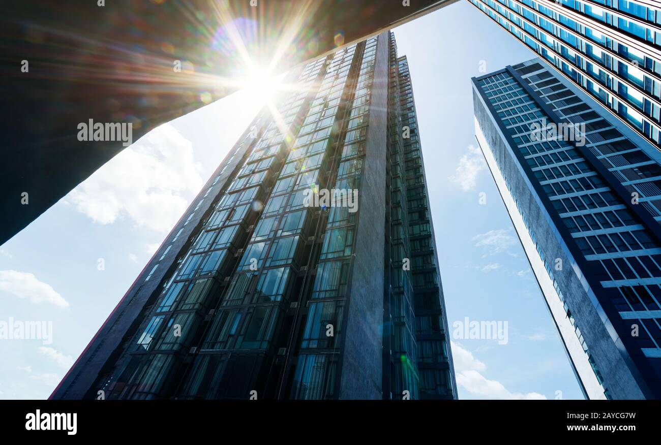 Vista a basso angolo dei grattacieli aziendali moderni comuni con sole in fioca. Foto Stock